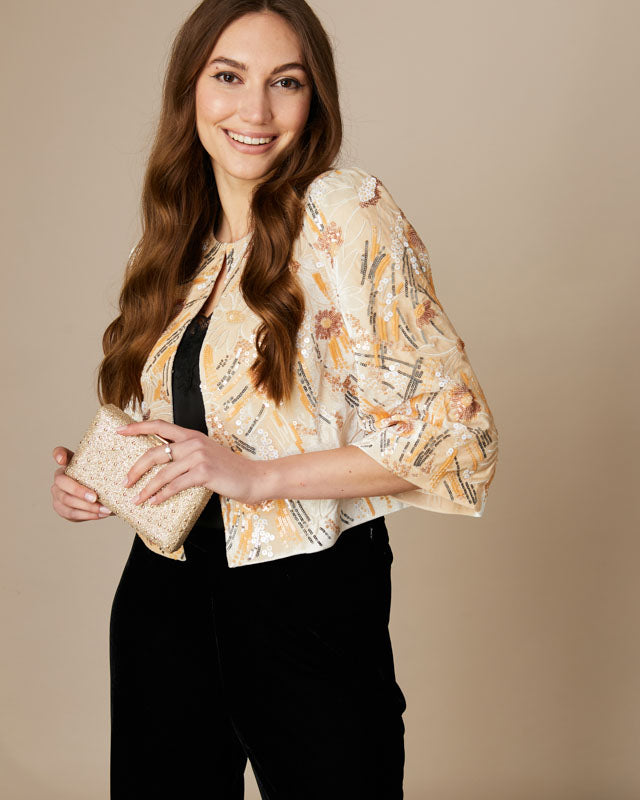 Fee G Athena cropped cream beaded jacket with sequin detail styled over a dress.