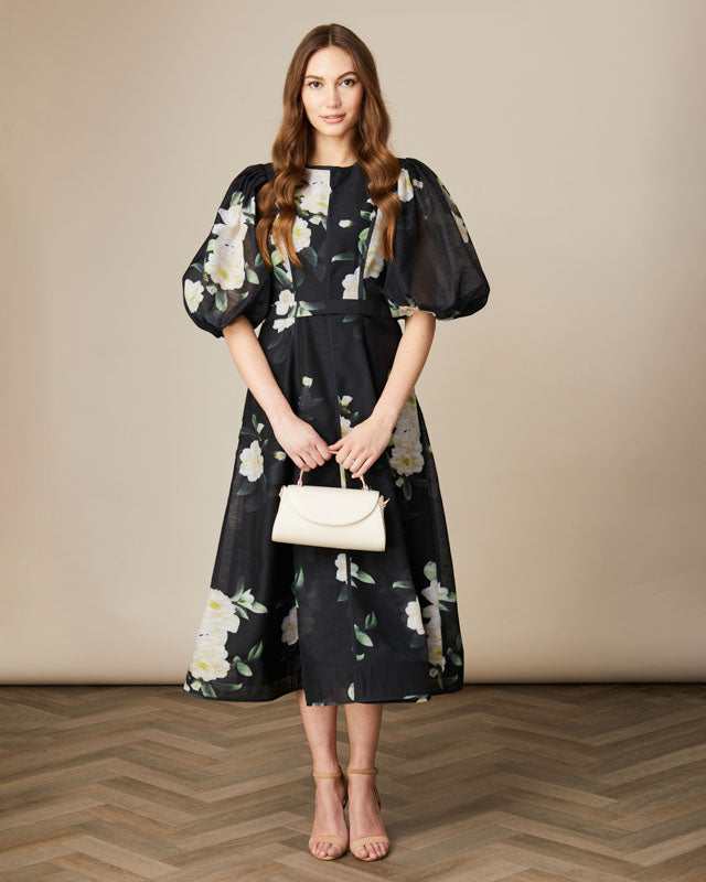 Model wearing Fee G Kate black floral puff sleeve occasion dress with fitted waist and voluminous skirt.