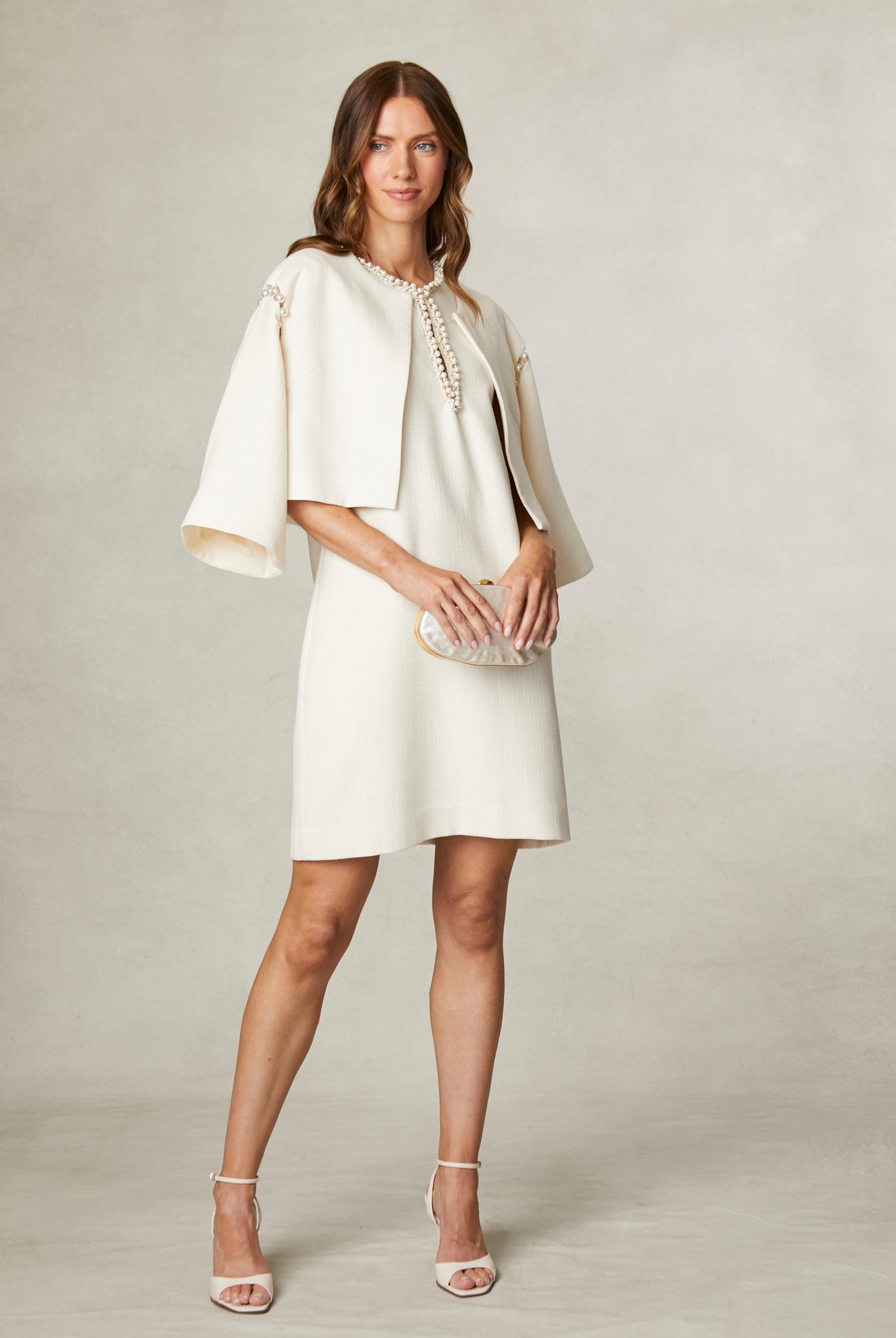 Side view of Fee G Lucy pearl neck shift dress worn with Feeg Cape