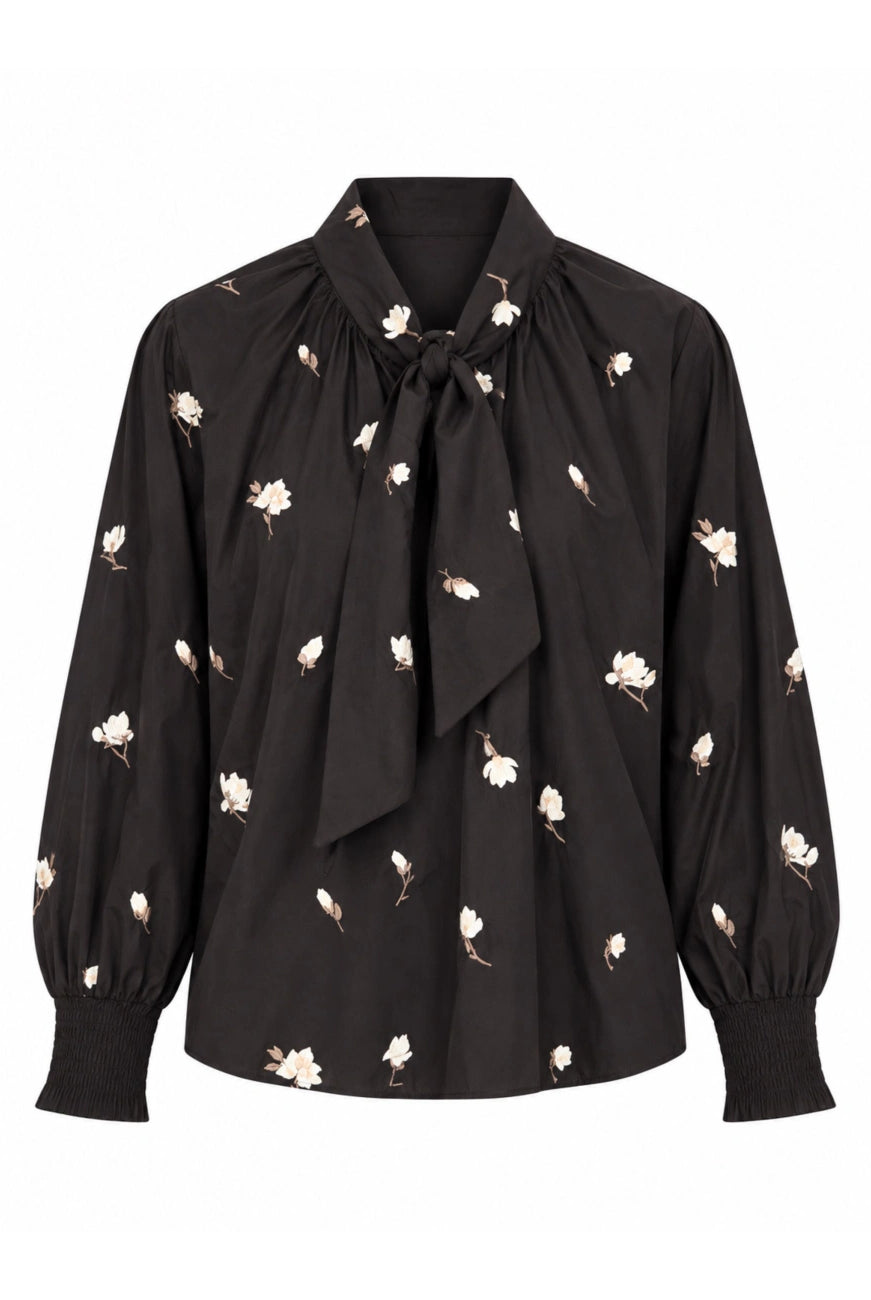 Gustav Erene dark brown floral blouse with ivory flower motifs, statement tie-neck bow and long sleeves with smocked cuffs – front view.