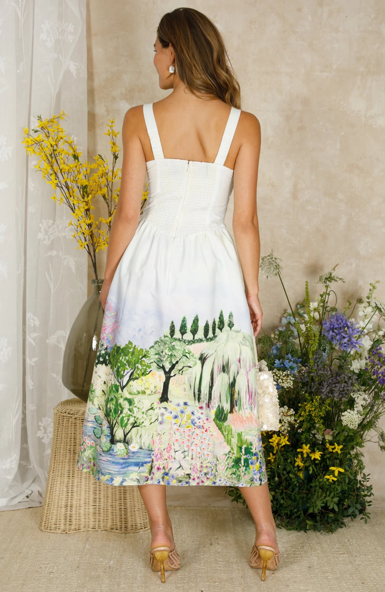 Model wearing Hope & Ivy Celine summer dress in cottage garden setting - back view