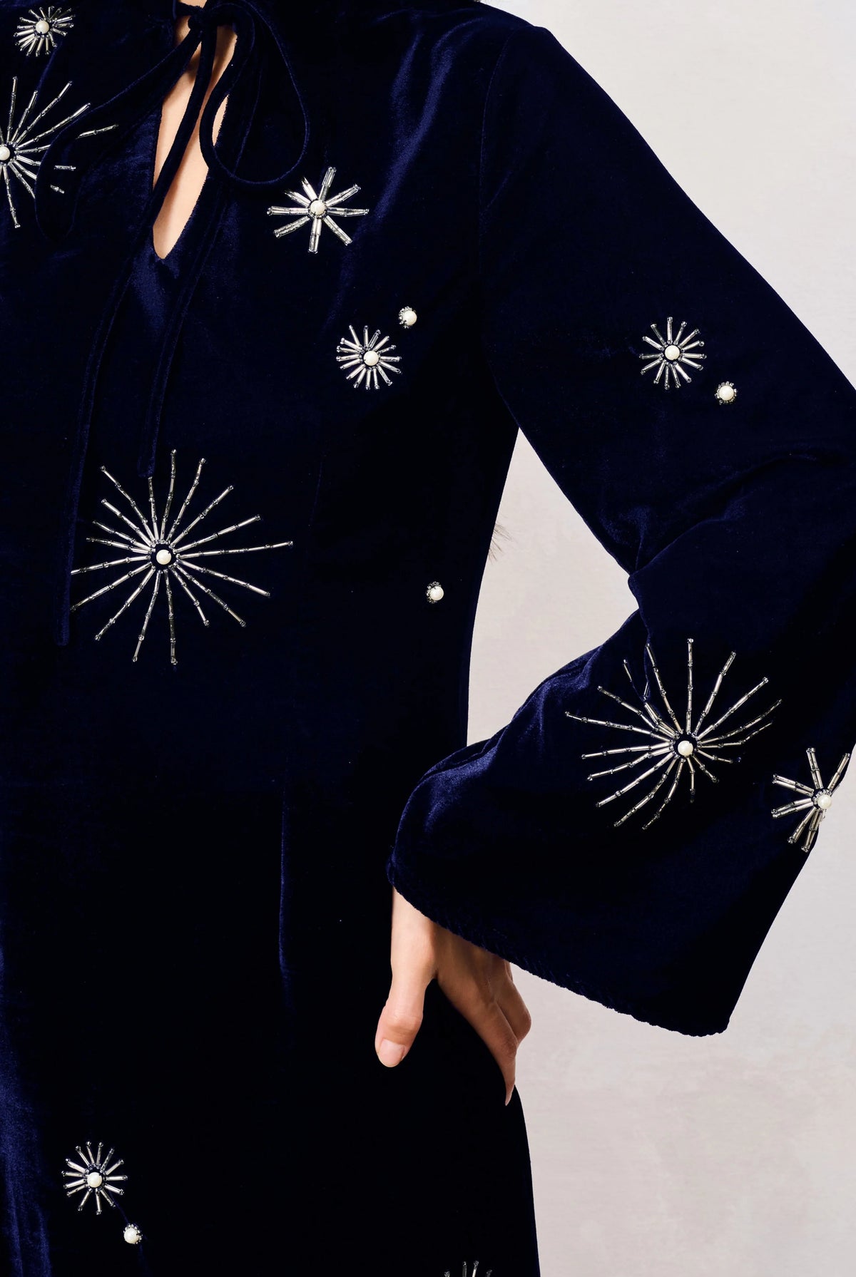 Close-up of Hope & Ivy Orelia navy velvet dress showing silver celestial starburst embellishments on the sleeve and bodice.
