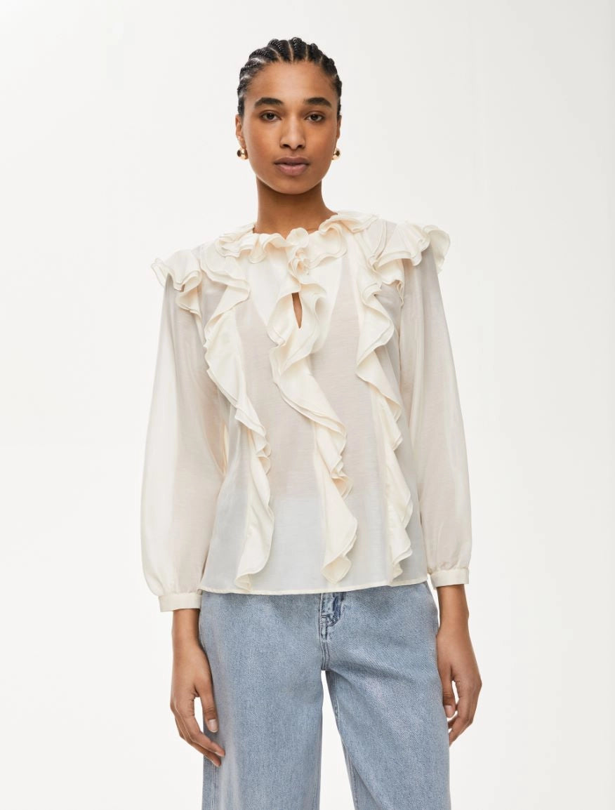 Close-up of ruffle detail iblues top and light sheer texture in ivory silk blend