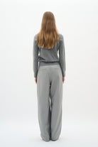 Back view of model wearing grey crew neck cardigan and grey wide-leg trousers