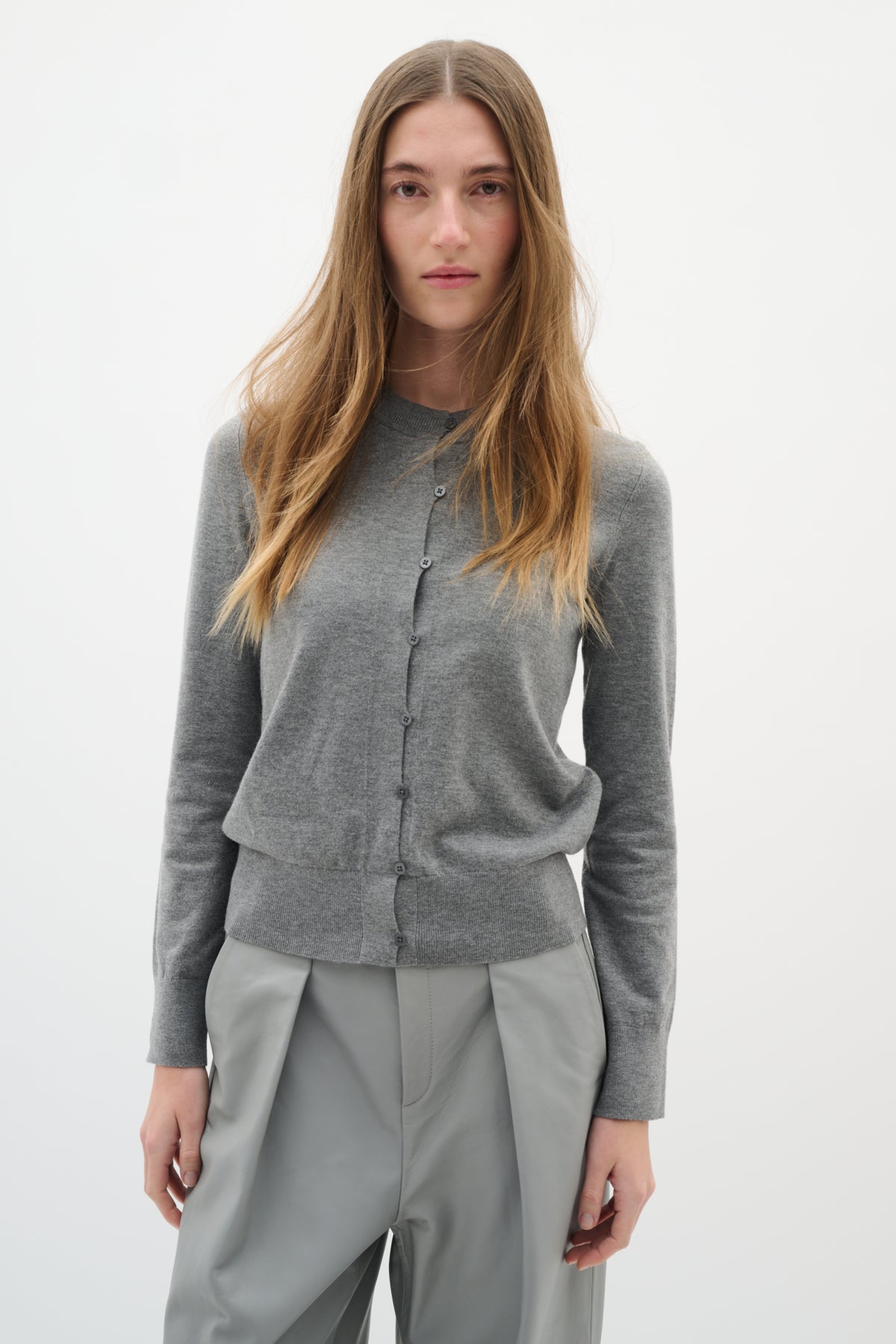 Mid-length view of grey cardigan styled with tailored trousers