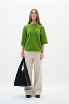 Full body view of model wearing InWear Bryelle beige bootcut trousers and green top