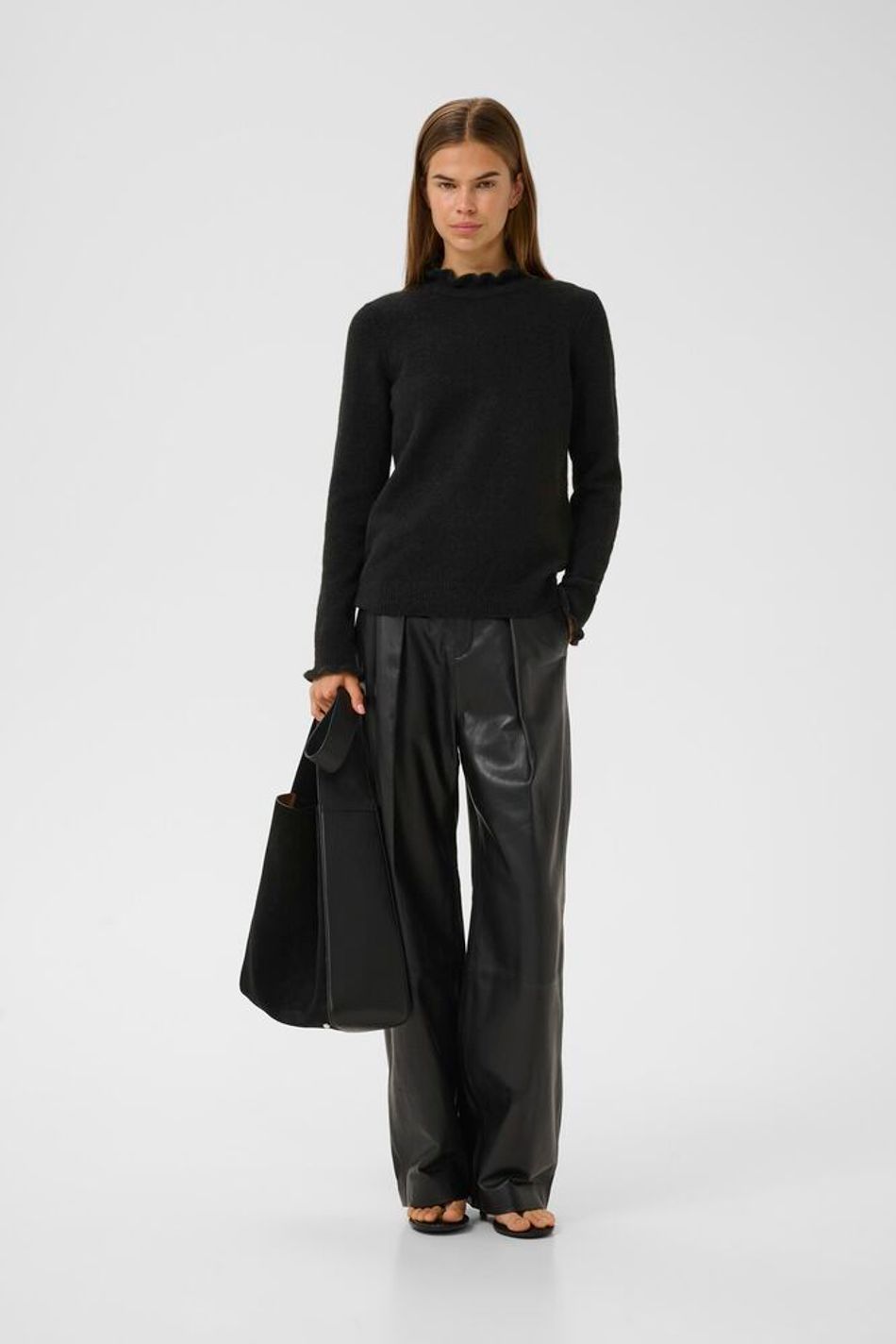 Model wearing black InWear Anaja frill detail jumper with leather trousers.