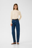 Model wearing cream InWear Anaja frill high neck jumper styled with jeans.