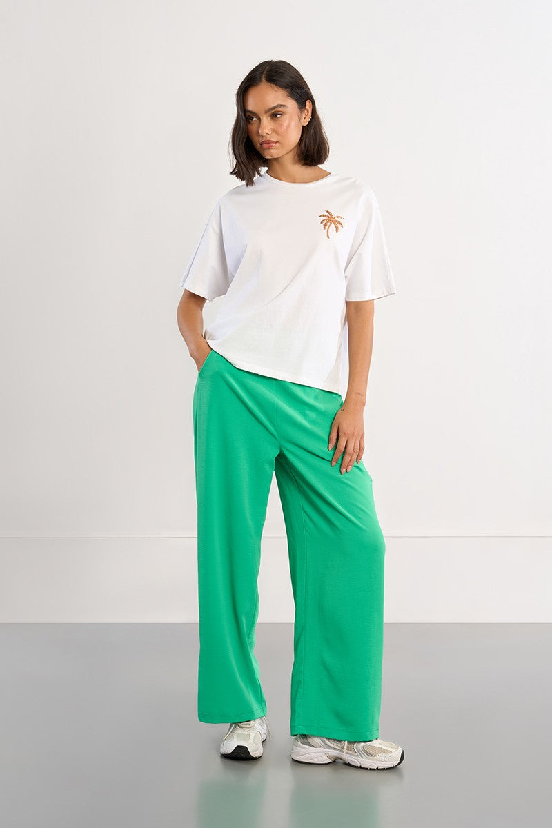 Lili Sidonio white oversized palm tree T-shirt styled with green trousers