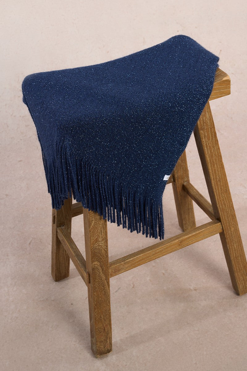 Close-up of Molly Bracken navy women’s scarf folded on stool, showing fringe texture