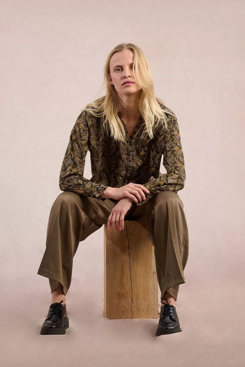 Seated model styling Molly Bracken khaki paisley blouse with relaxed fit