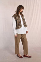 Molly Bracken sleeveless leopard print jacket styled over white shirt
And beige trousers