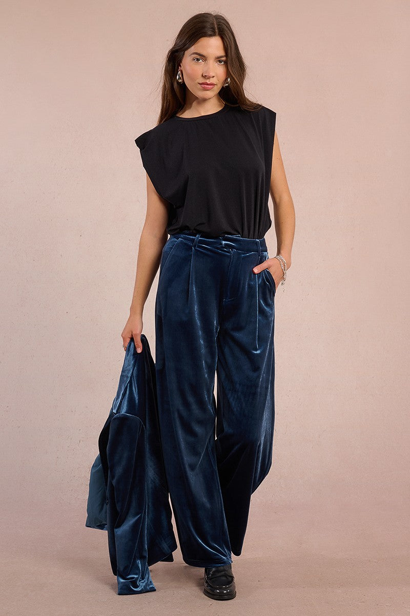 Model walking in wide leg velvet trousers by Molly Bracken, paired with black sleeveless top