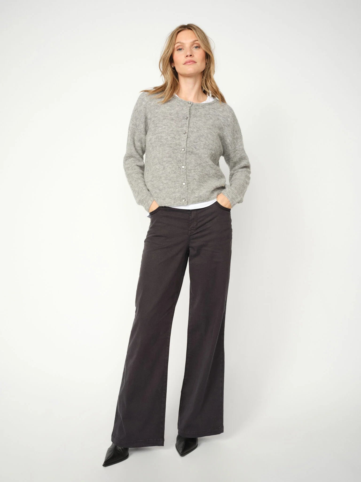 Model wearing Mos Mosh Dara Treasure Wide Leg Trousers in dark grey with grey cardigan and pointed heels.