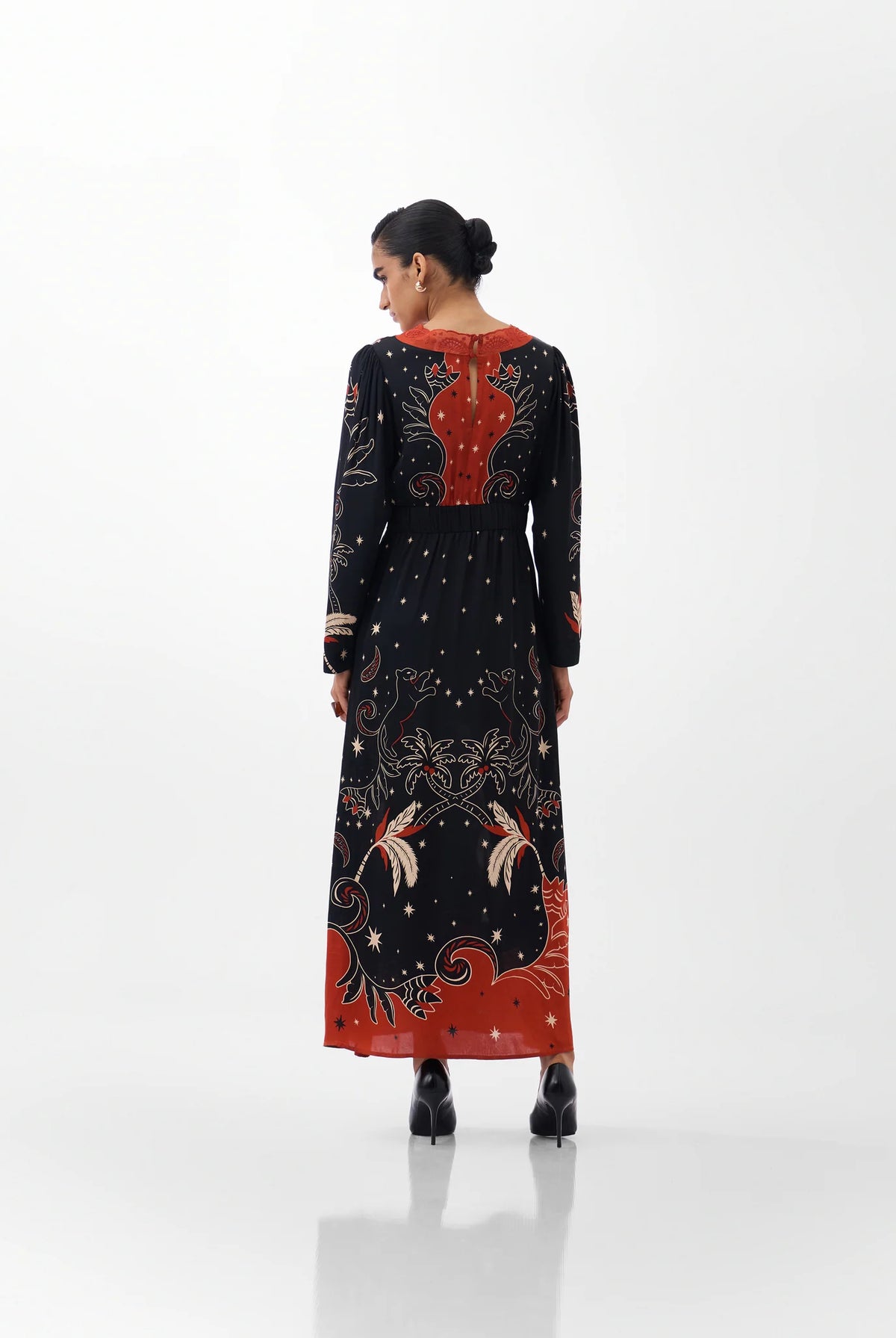 NOIB Aura Old Rose black printed maxi dress with orange-red back detail and patterned hem – rear model view.