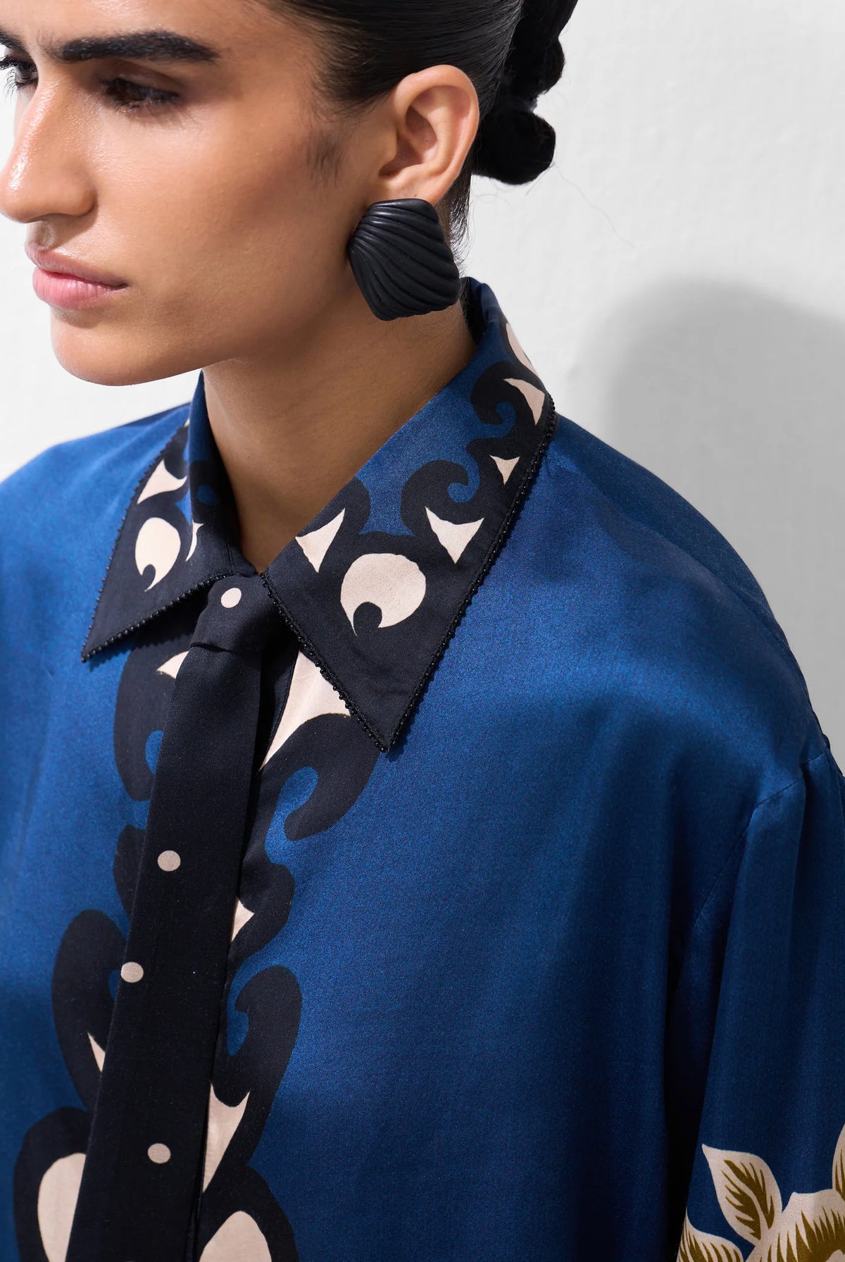 NOIB Iris blue ornamental floral shirt with dark printed collar and tie-neck detail – close-up model view.