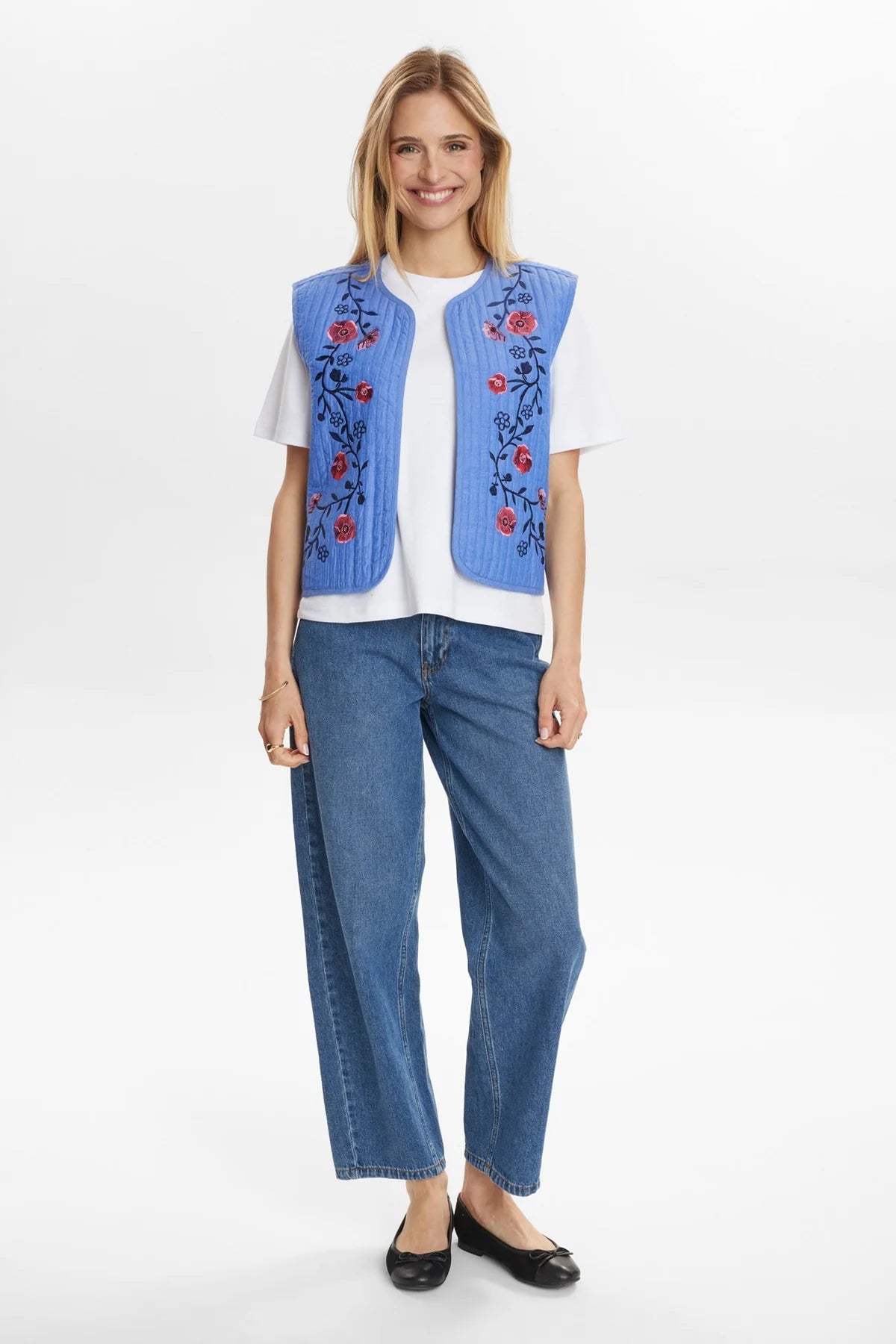 Side view of blue embroidered gilet layered over casual outfit