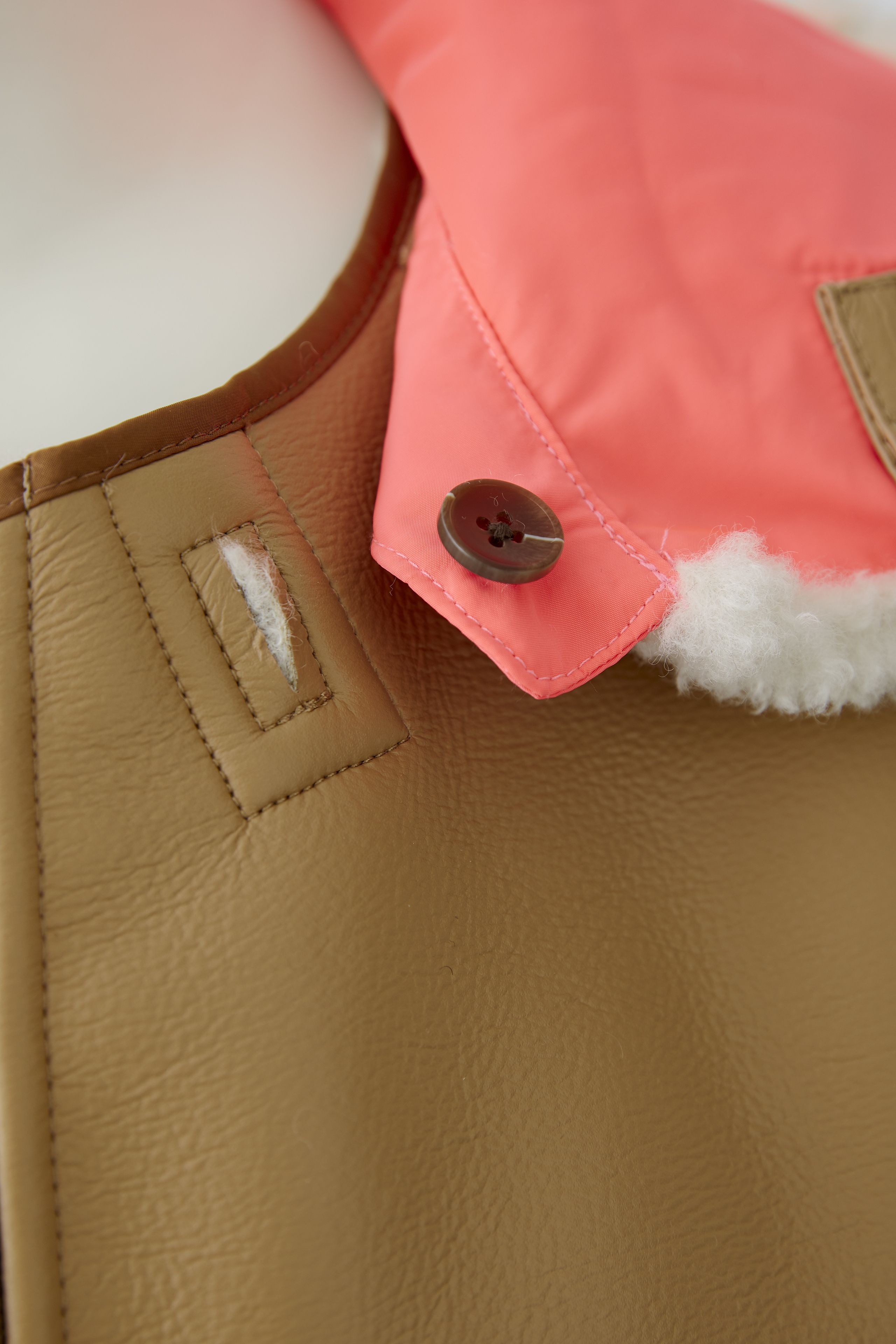 Oui reversible tan jacket — detail of neon contrast patch and button at collar.