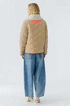 Oui reversible jacket — back view, ecru side with quilted sleeves and neon tab at collar.