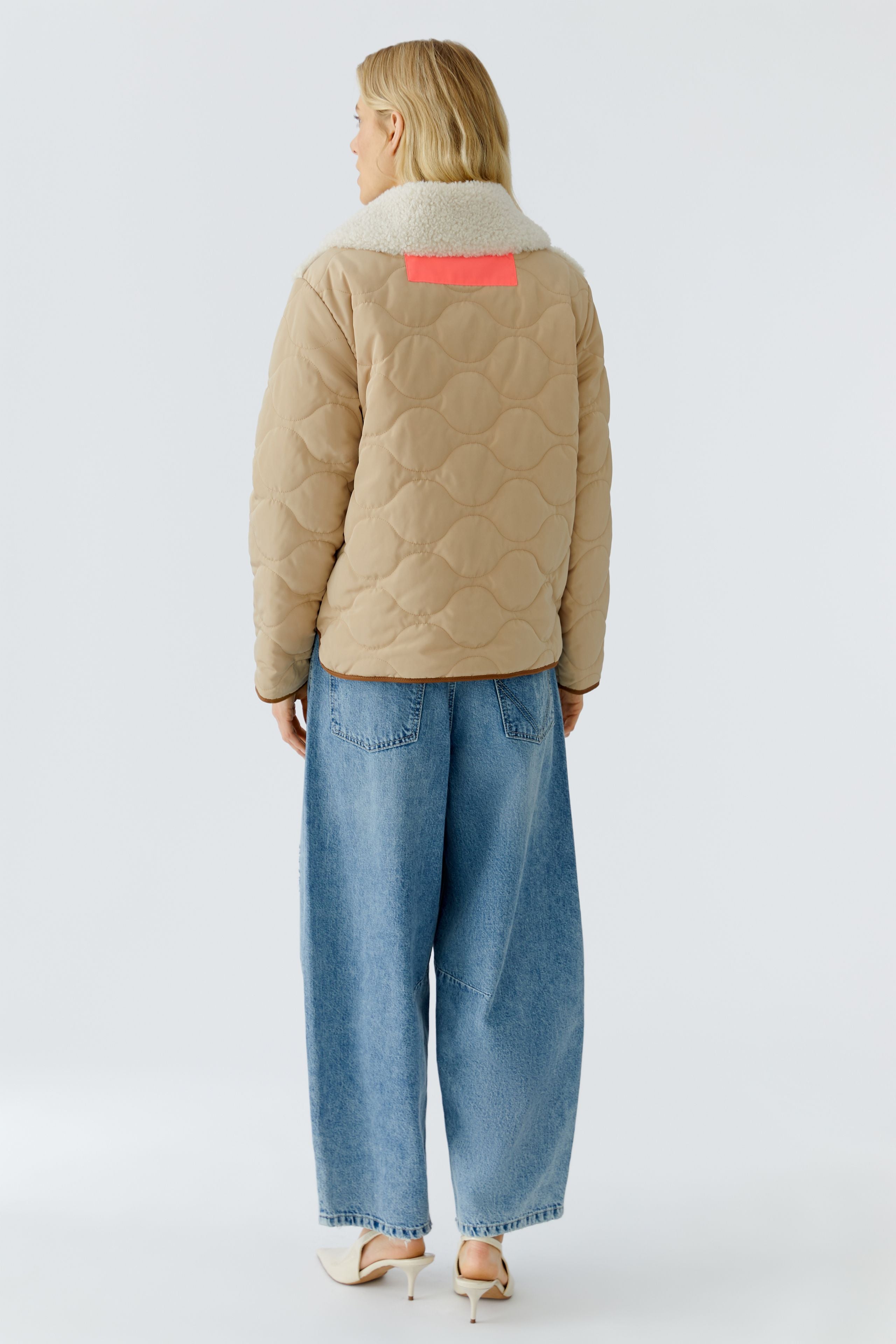 Oui reversible jacket — back view, ecru side with quilted sleeves and neon tab at collar.