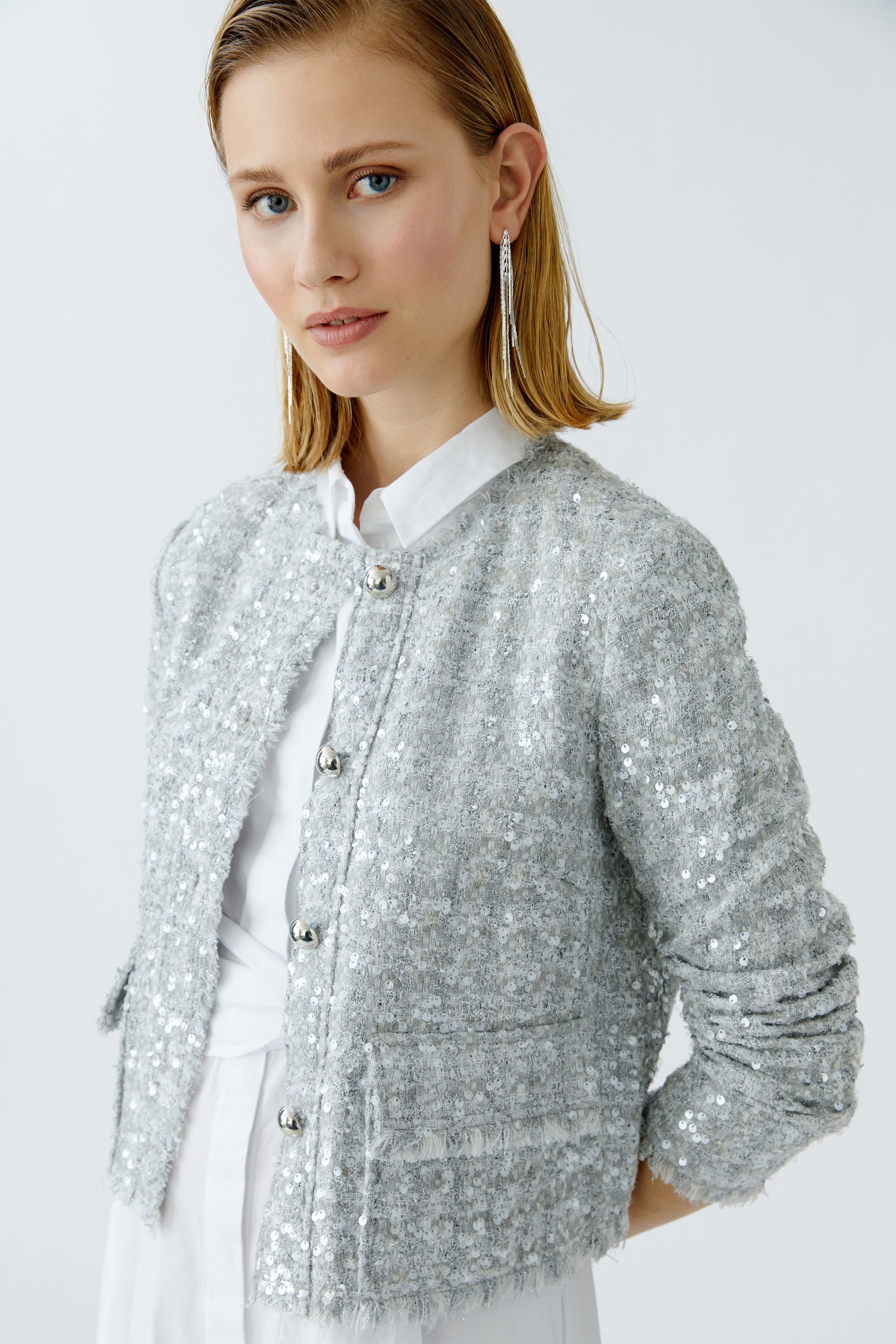 Model wearing silver bouclé jacket with white dress