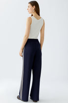 Model wearing wide-leg navy slip-on trousers with relaxed cream vest top, back view