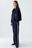 Model wearing Oui navy wide-leg trousers with cream side stripes, styled with matching jacket
