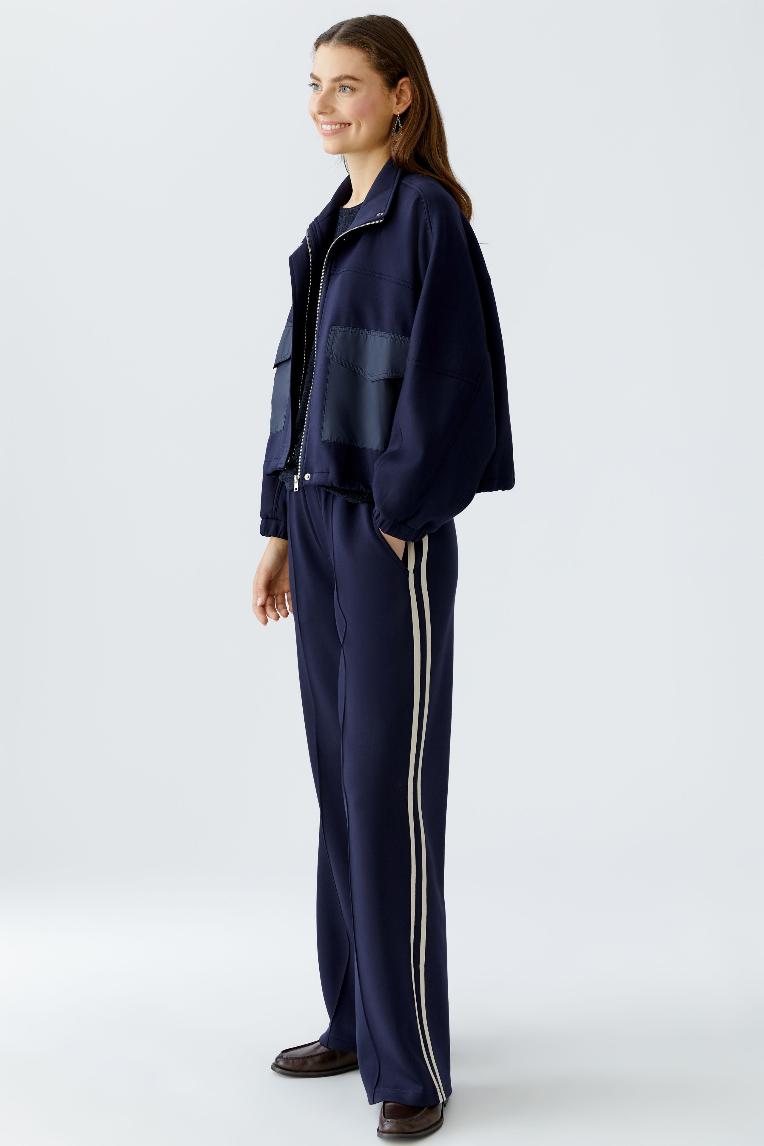 Model wearing Oui navy wide-leg trousers with cream side stripes, styled with matching jacket