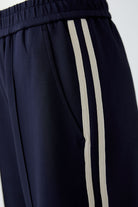 Close-up of elasticated waistband and cream contrast stripes on Oui navy trousers