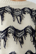 Close-up of a sweater with funky fringe designs and fringes.