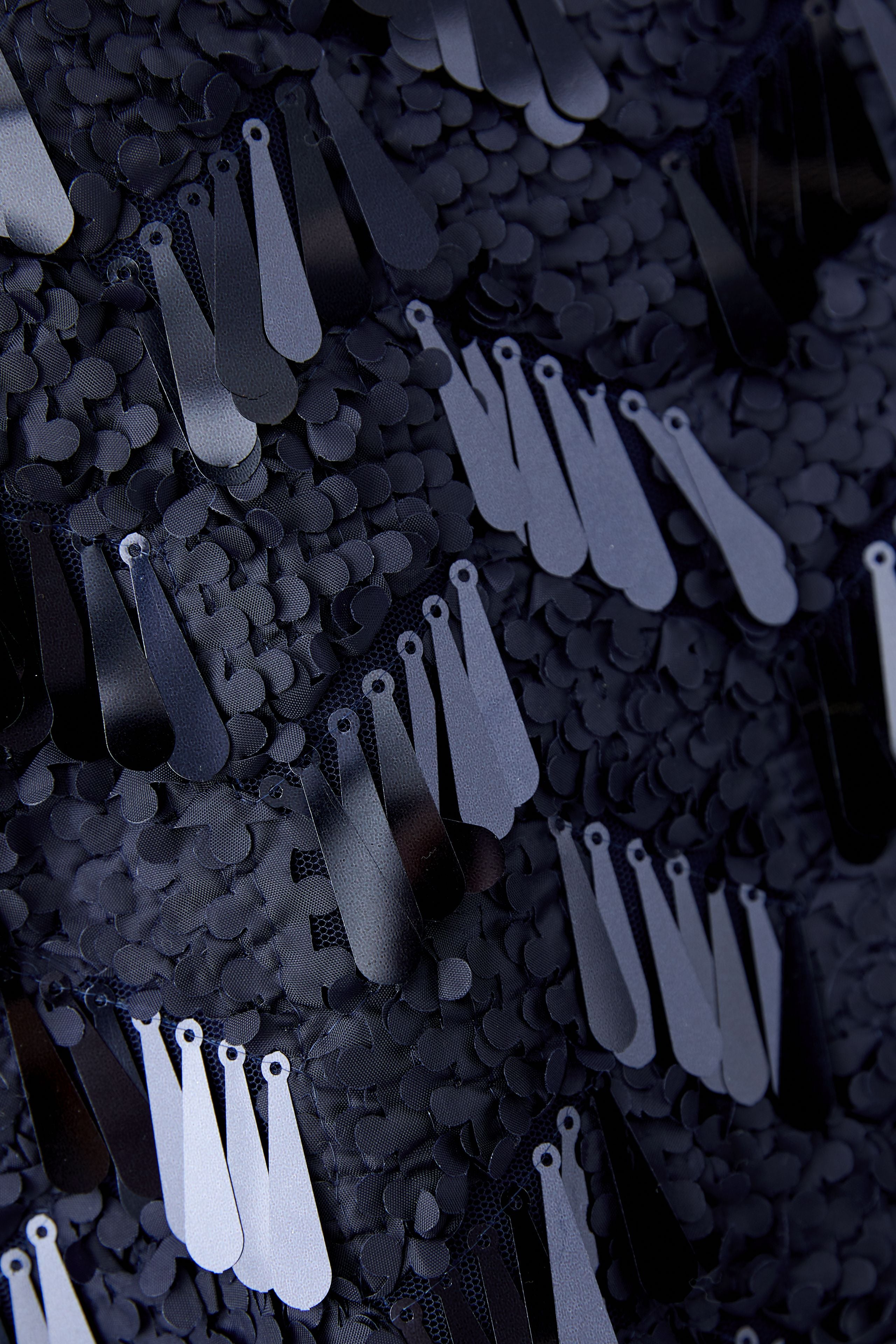 Close-up view of matte and glossy sequin detail on navy cam