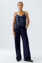Model wearing Oui navy sequin cami top with matching navy trousers