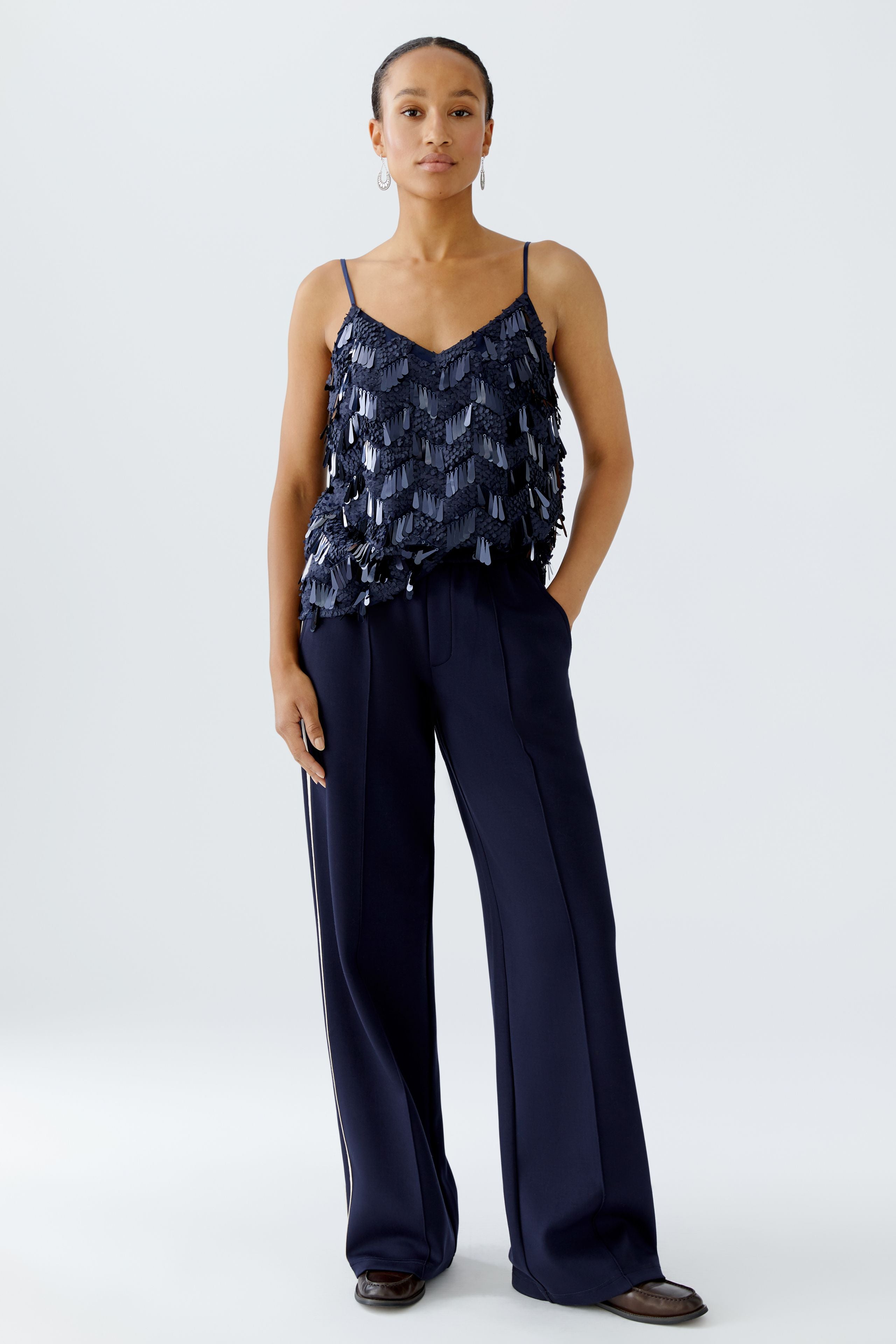 Model wearing Oui navy sequin cami top with matching navy trousers