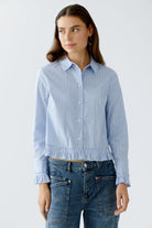 Model standing facing forward in blue and white ruffle blouse and casual jeans