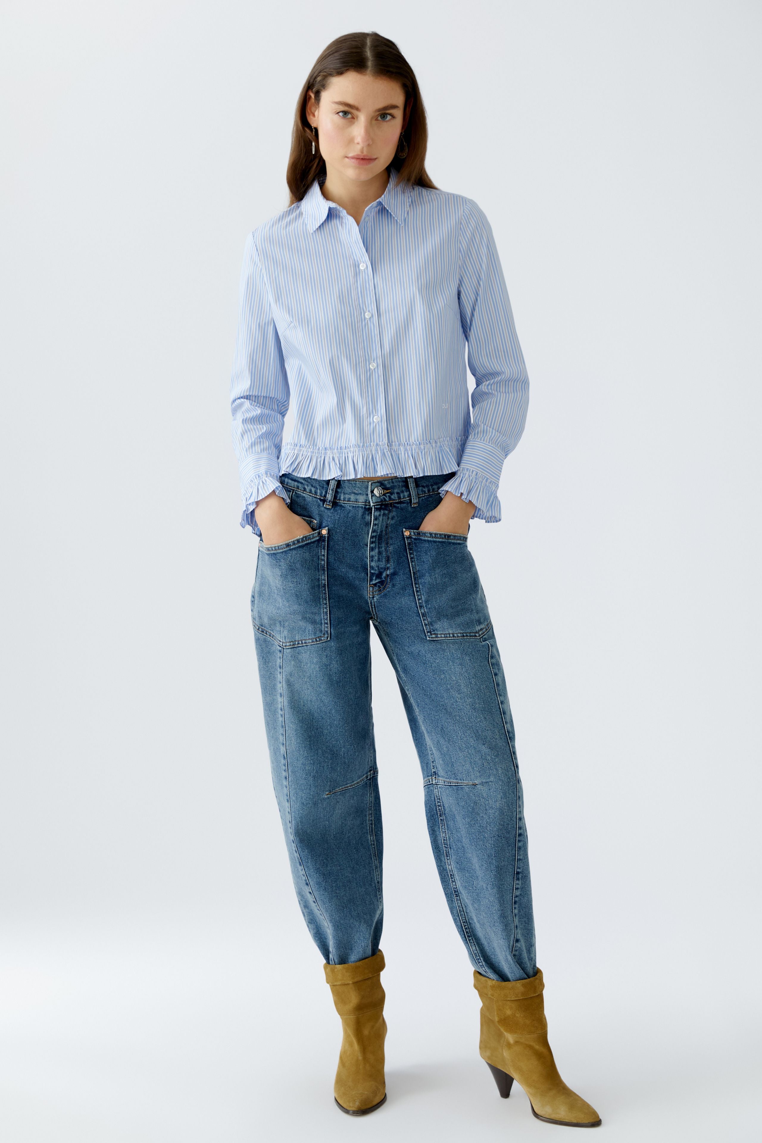 Front full-body view of model wearing Oui blue and white striped blouse with ruffle hem and relaxed jeans