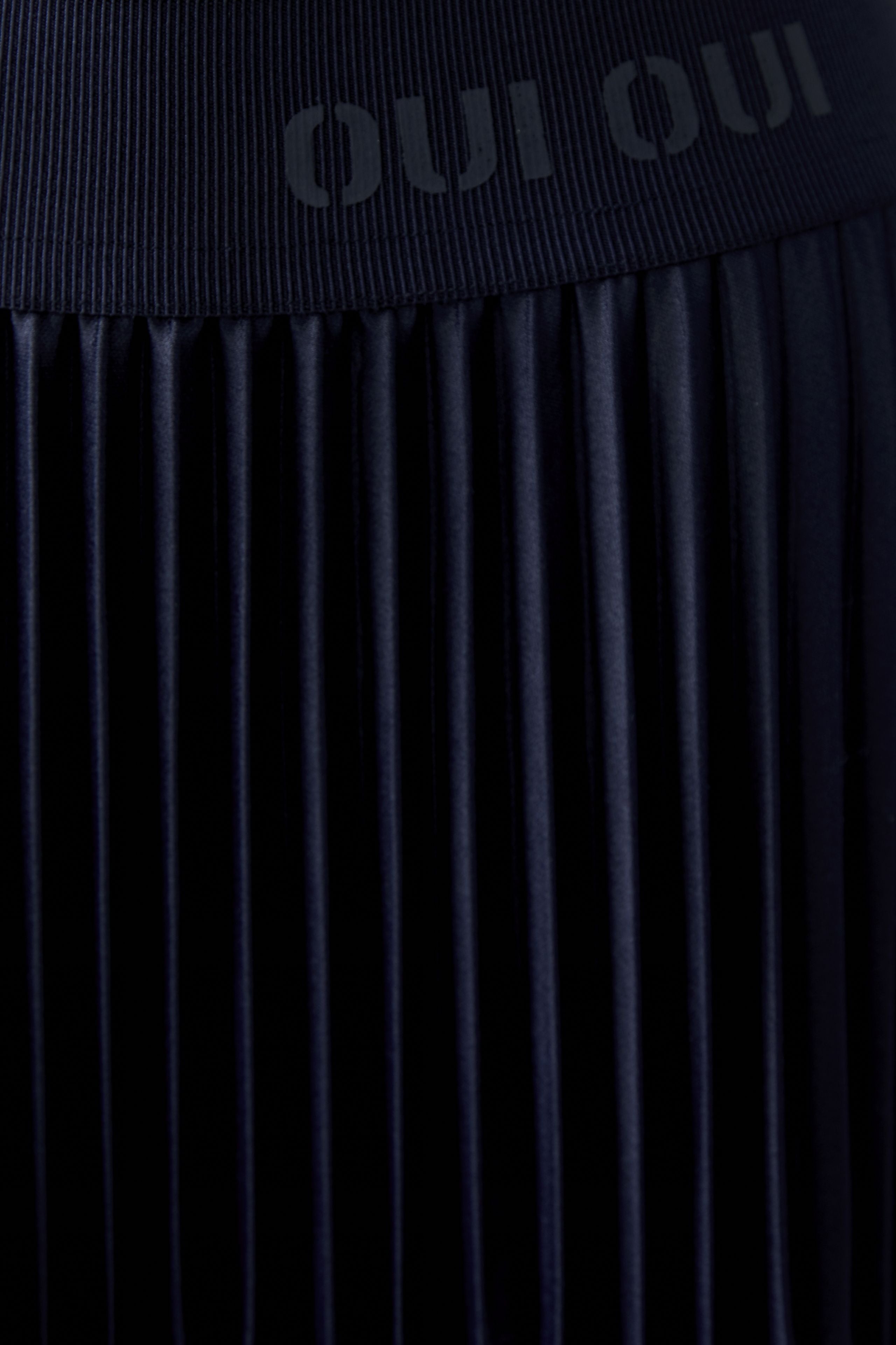 Detail of glossy navy pleated midi skirt and fabric texture