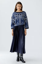 Model in Oui navy silky pleated midi skirt with blue patterned jumper