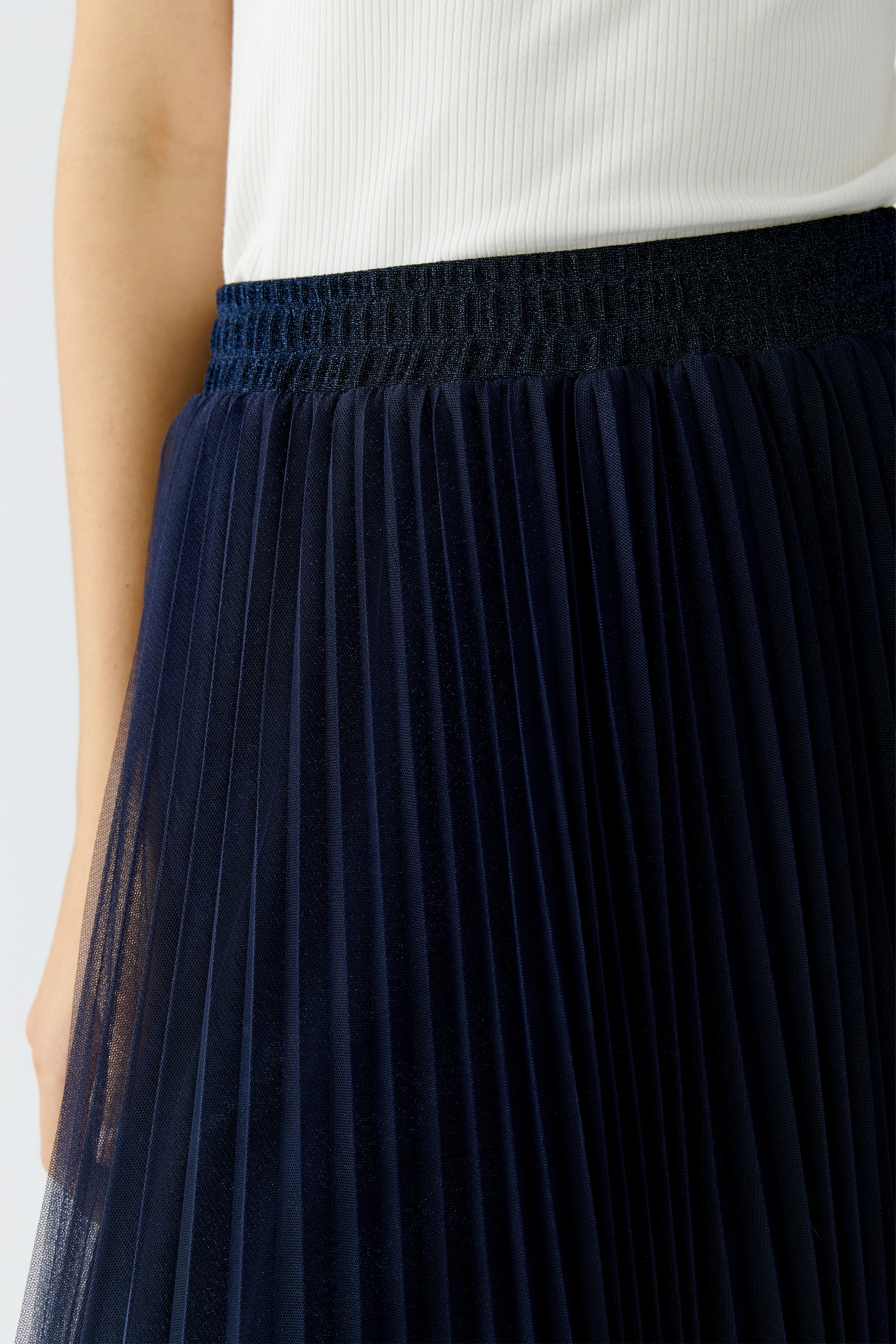 Side view of navy pleated skirt showing mesh volume