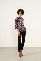 Model wearing Sisters Chantel animal print blouse front view paired with black trousers
