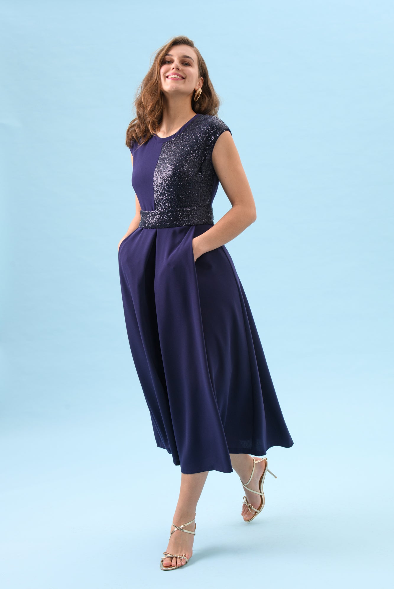 Full-length view of Sisters Feya ink blue sequin fit and flare midi dress with pockets