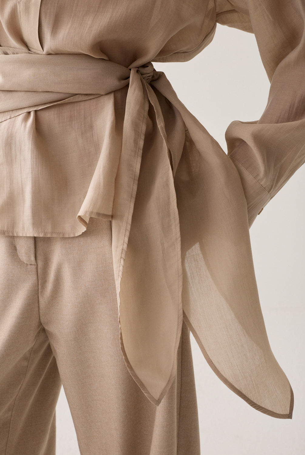 Close-up of Summum wrap waist tie detail top with long sleeves
