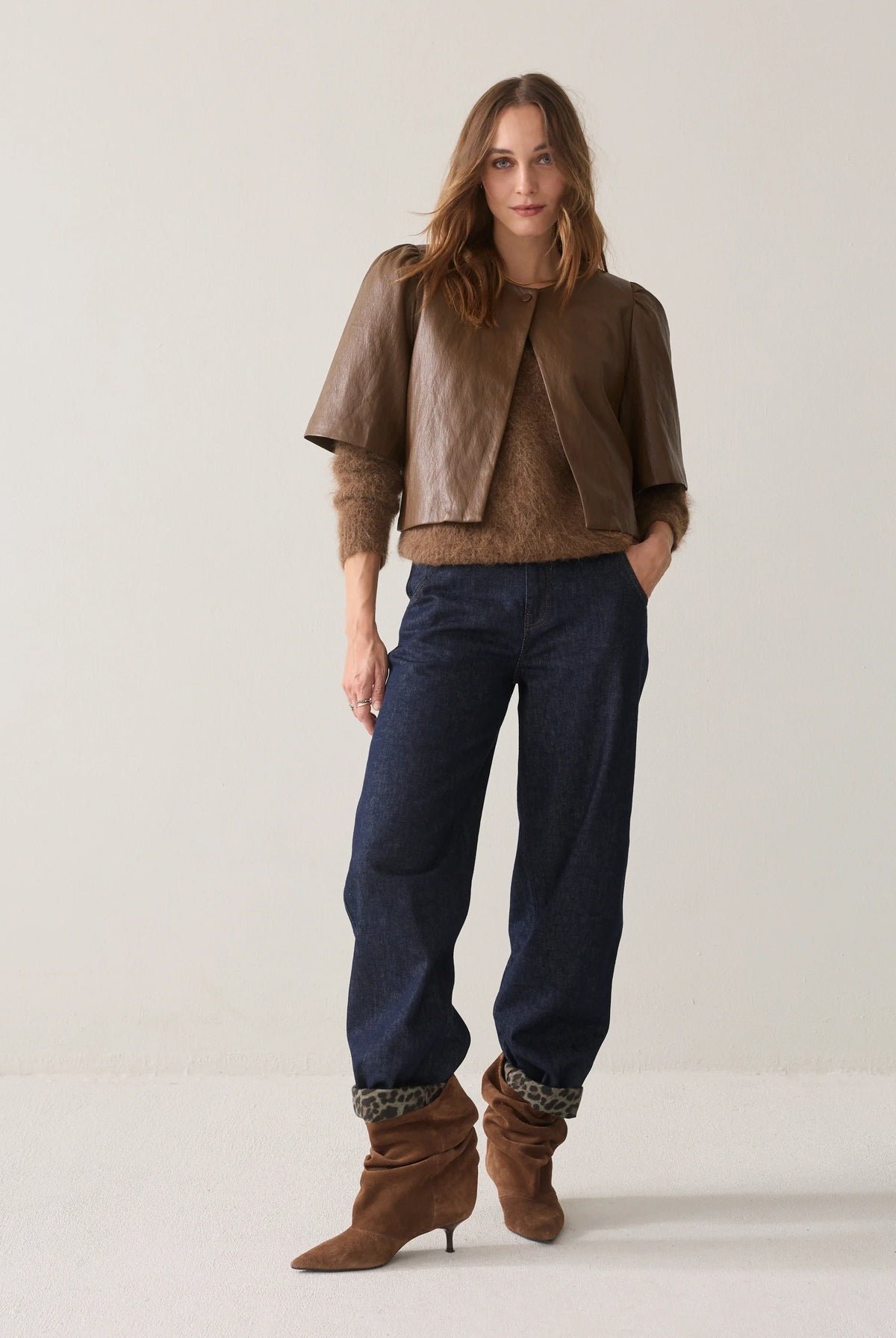 Summum short brown faux leather jacket styled with navy trousers and brown boots – full model view