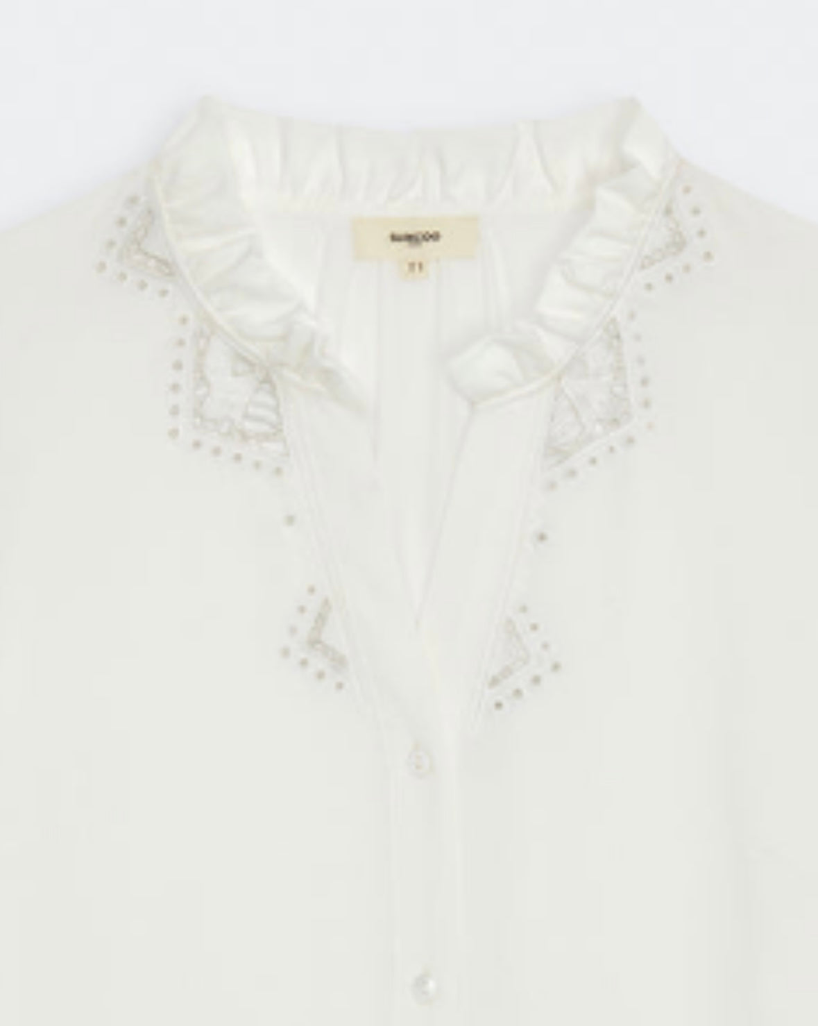 Close up of frilled neckline on cream blouse with embroidered sleeves by Suncoo
