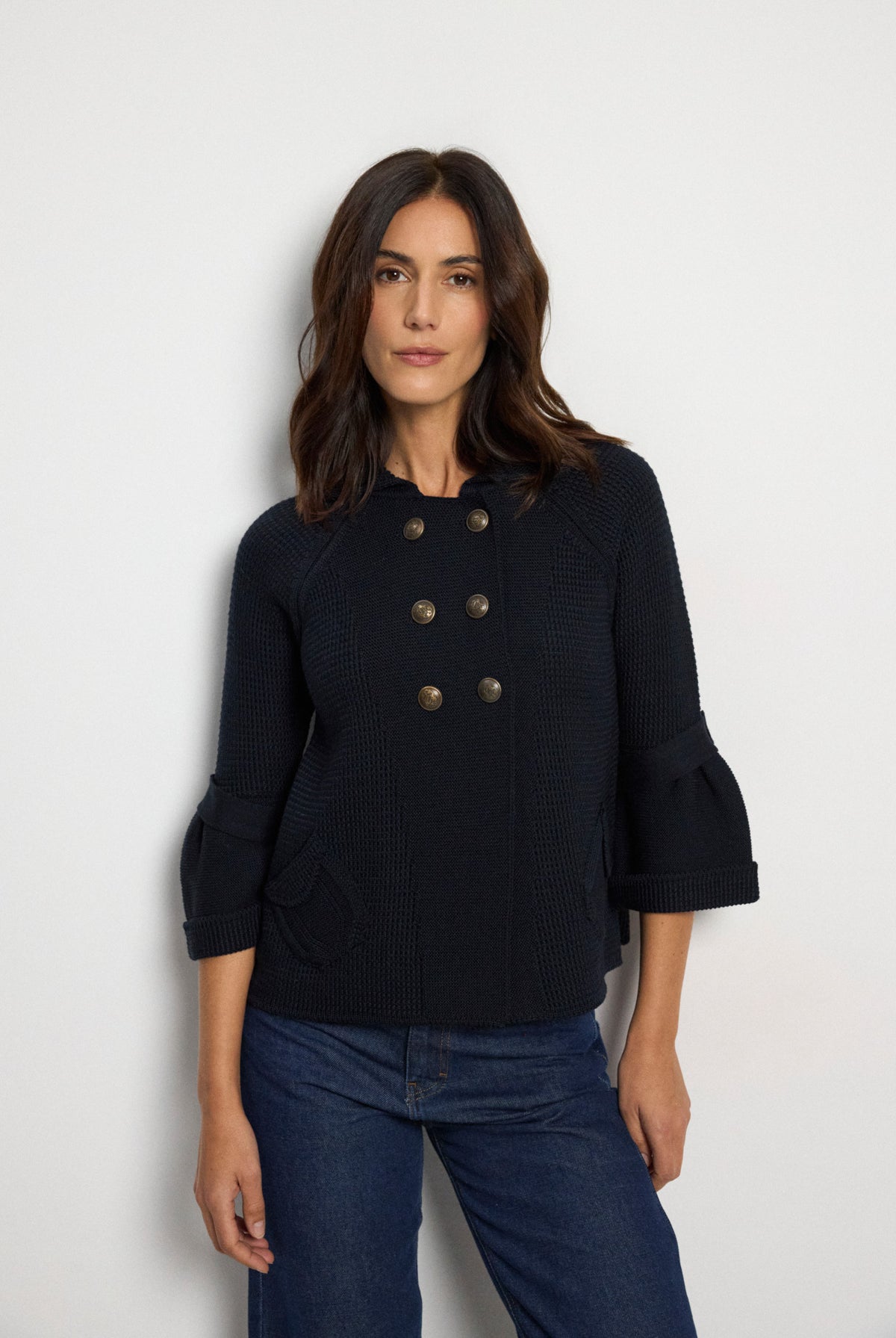 Tinta Pacifica navy double-breasted knitted jacket with metallic buttons, flared sleeves, collar and flap pockets – front model view.