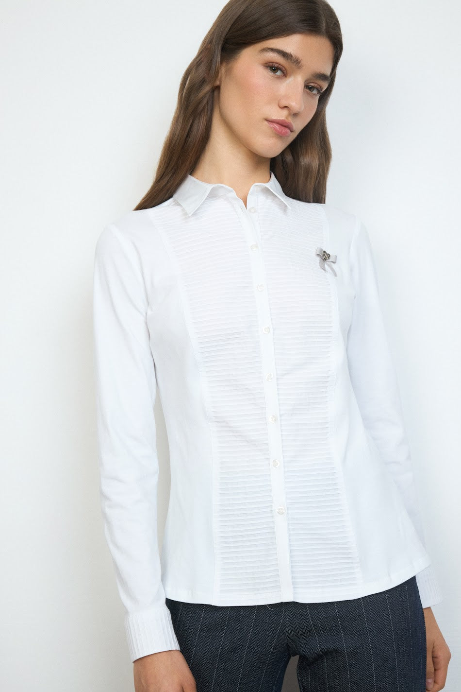 Model wearing Tinta Soraya white shirt with pintuck detailing and bow brooch