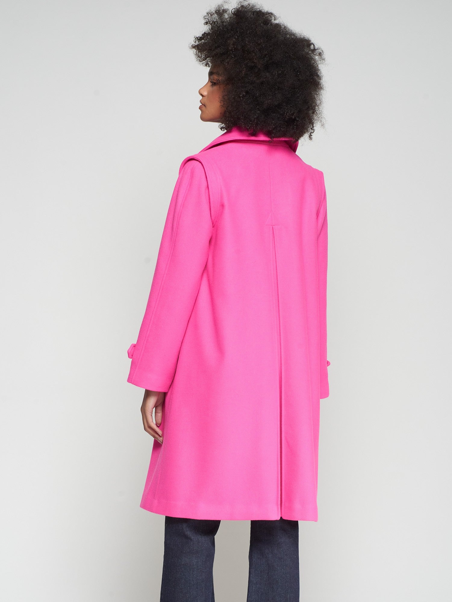 Back View Women’s pink trench coat with buttoned cuffs and welt pockets.