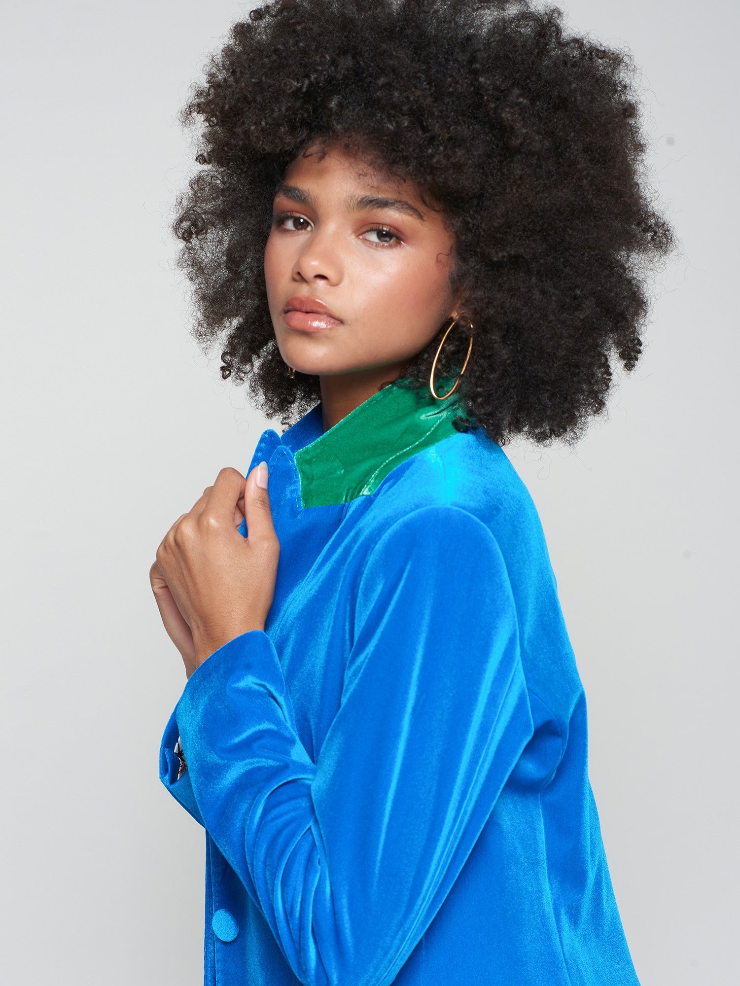 Vilagallo blue velvet blazer with green contrast collar detail and gold hoop earrings