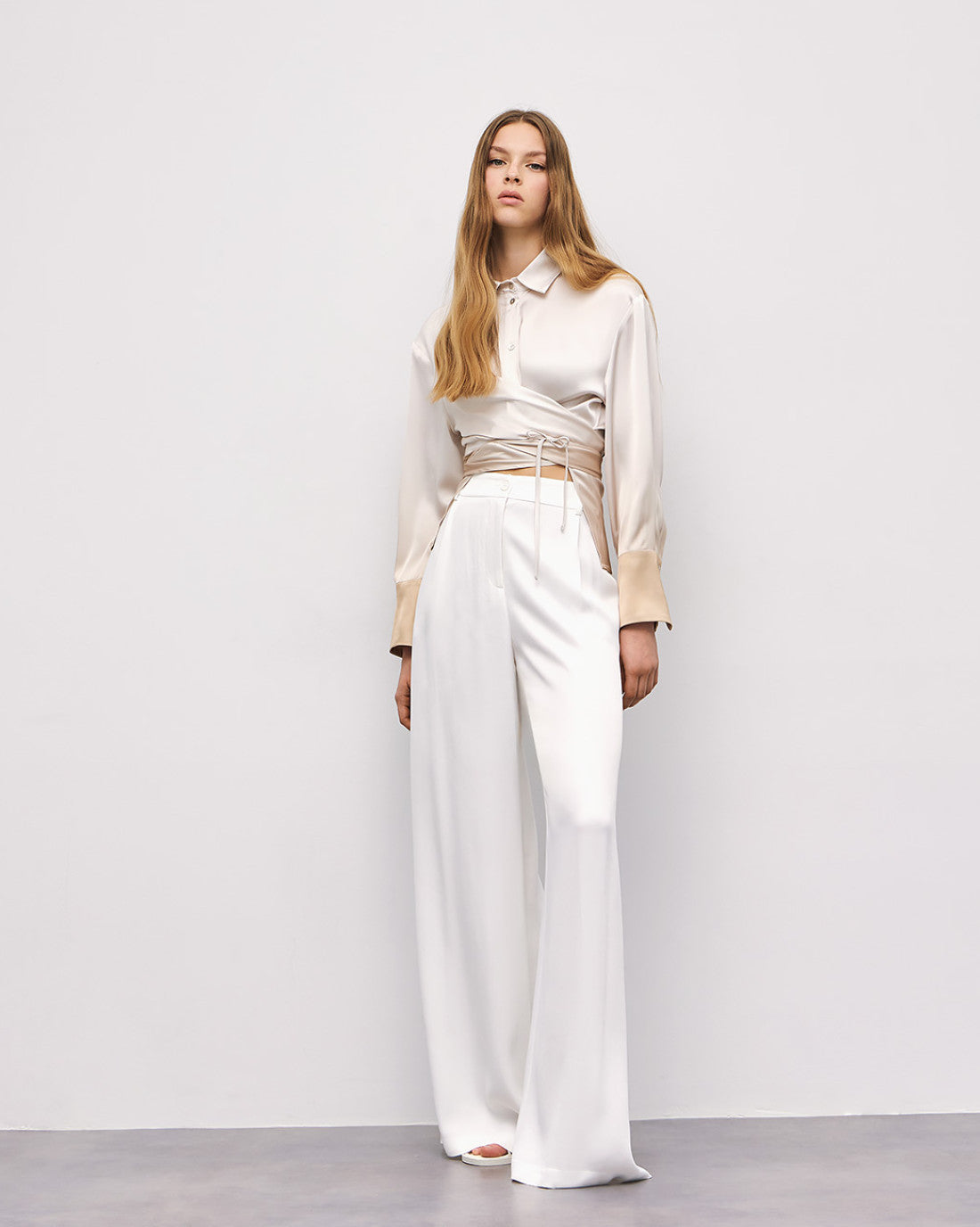 Model in cream ombré wrap shirt with gold cuffs styled for evening look