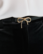 Access Fashion thin black faux leather belt with gold bow buckle close up.