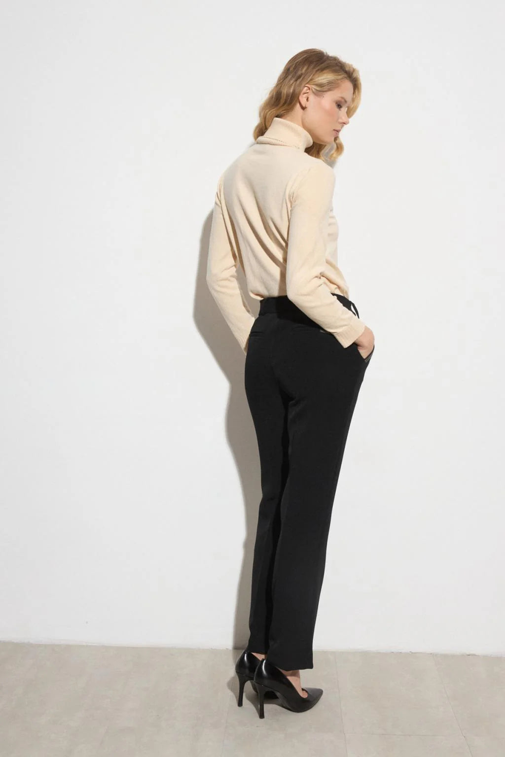 Side view of Bariloche Luncaria tailored black trousers with stud detailing at pocket.